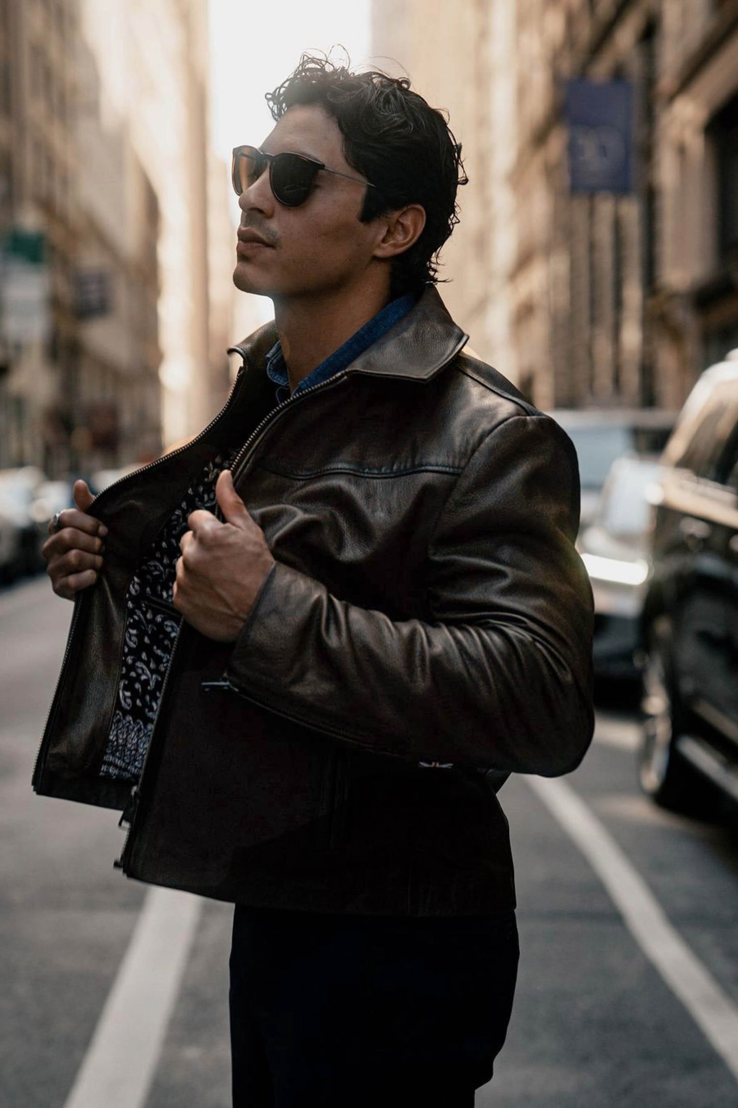 Model wearing a brown leather jacket with sunglasses