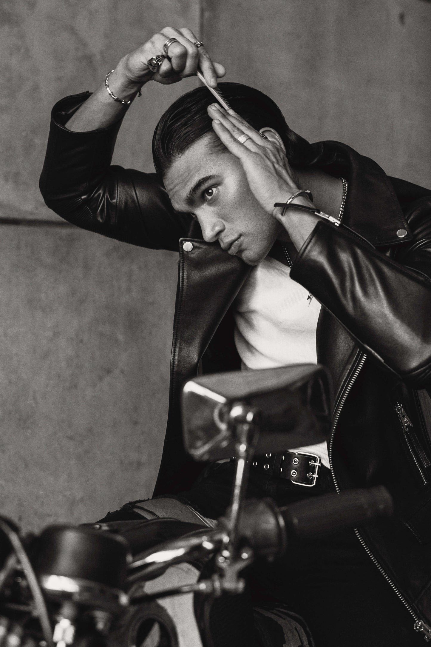 Man doing his hear with a comb on a motorbike whilst wearing a black leather biker jacket